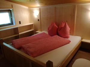 a bed in a cabin with red pillows on it at Tanterhütte by Tanterhof in Schwendau