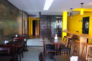a restaurant with wooden tables and chairs and yellow walls at Sudoeste Hotel in Goiânia