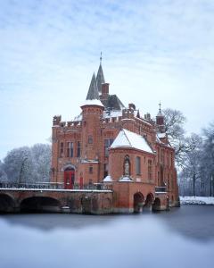 a large red brick building with a bridge in the water at Castle ten Berghe Château in Bruges