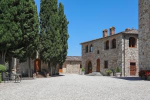un grand bâtiment en pierre avec des arbres devant lui dans l'établissement Castello La Leccia, à Castellina in Chianti