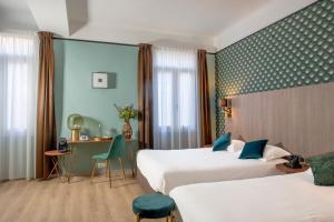 um quarto de hotel com duas camas e uma secretária em Hôtel Le Bristol em Avignon