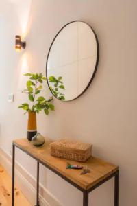 ein Spiegel an einer Wand über einem Tisch mit einer Pflanze in der Unterkunft Sweety Balcony Porto Center in Porto