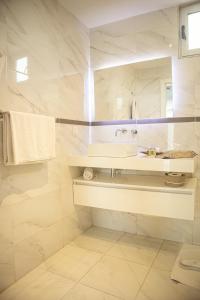 a white bathroom with a sink and a mirror at THE PALMS Luxury Boutique Hotel in Dakar