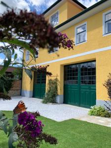 Casa amarilla y verde con puertas verdes de garaje en Ferienhaus Karoline, en Pulkau