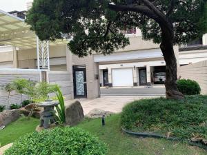 a tree in front of a building with a garden at 亨泰民宿2-8人包棟 in Chaozhou