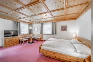 a bedroom with a bed and a desk and a tv at Hotel Nevada in Samnaun