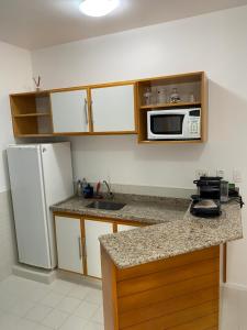 a kitchen with a white refrigerator and a microwave at Flat Boulevard Riviera de São Lourenço - Praia in Riviera de São Lourenço