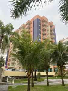 a tall building with palm trees in front of it at Flat Boulevard Riviera de São Lourenço - Praia in Riviera de São Lourenço