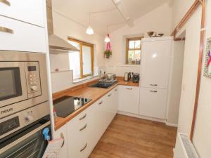 eine Küche mit weißen Schränken und einem Waschbecken in der Unterkunft Bwthyn Gwyn Ty'n Y Pant in Pwllheli
