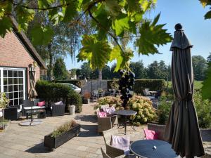 eine Terrasse mit einem Sonnenschirm, Tischen und Stühlen in der Unterkunft B&B-Hotel de Joremeinshoeve in Kaatsheuvel