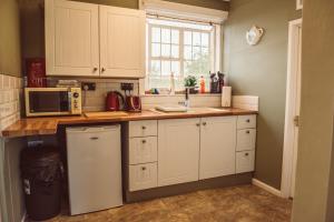 a kitchen with white cabinets and a sink at Penygelli Apartments in Newtown