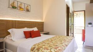 um quarto com uma cama grande e almofadas vermelhas em Kanaloa Pousada em Jericoacoara