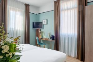a room with a bed, chair and a window at Hôtel Le Bristol in Avignon