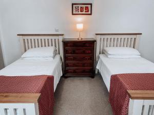 a bedroom with two beds and a dresser with a lamp at The Blenheim Buttery in Woodstock