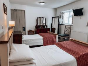 ウッドストックにあるThe Blenheim Butteryのベッド2台と鏡が備わるホテルルームです。
