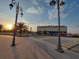 two street lights on a brick road with a building at Qasr Alshamal Hotel in Arar