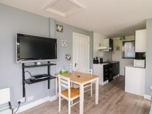 a kitchen with a table and a tv on a wall at SeaChange Annexe in Ballygarrett