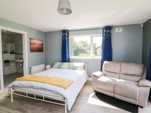 a bedroom with a bed and a couch and a window at SeaChange Annexe in Ballygarrett