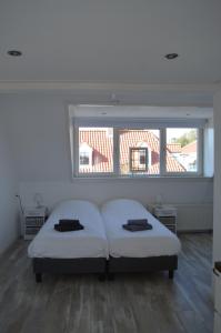 1 dormitorio con 2 camas y ventana grande en t Laege Uus en Burgh Haamstede