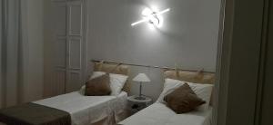 a bedroom with two beds and a light on the wall at MY BED affittacamere in Cuneo