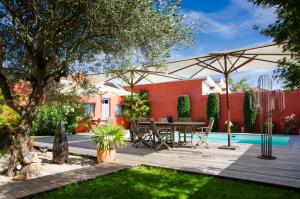 um pátio com uma mesa e guarda-sol e uma piscina em La Ferrade Chambres d'Hôtes B&B em Bègles