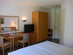 a bedroom with a bed and a desk with a television at Landgasthof Adler in Künzelsau