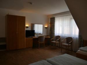 a hotel room with a desk with chairs and a television at Landgasthof Adler in Künzelsau