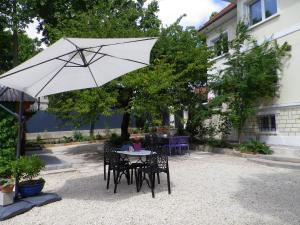 una mesa y sillas con una sombrilla blanca en Villa Sunshine en Bagneux