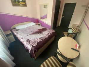 a bedroom with a bed with purple walls and chairs at Hotel ALTEYA in Moscow