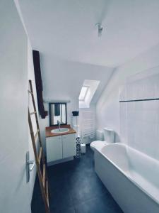 uma casa de banho branca com uma banheira e um lavatório em Le Cosy B em La Gouesnière