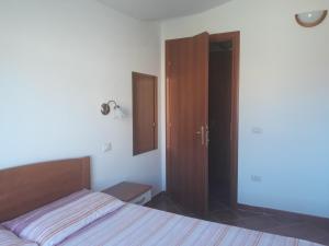 1 dormitorio con cama, armario y espejo en Il sughereto, en Àrbatax