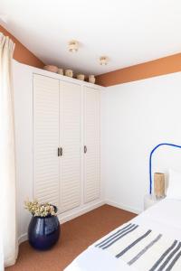a bedroom with white cabinets and a blue vase at Hôtel Le Sud in Juan-les-Pins