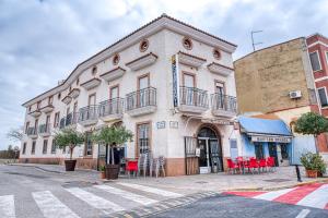 un edificio con sillas rojas y mesas en una calle en Hostal Nova Picanya, en Picaña