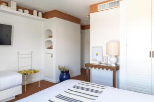 a bedroom with white walls and a bed and a tv at Hôtel Le Sud in Juan-les-Pins