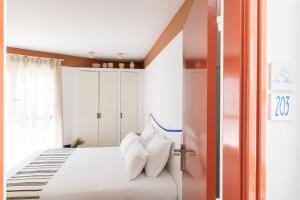 a bedroom with a white bed with white pillows at Hôtel Le Sud in Juan-les-Pins
