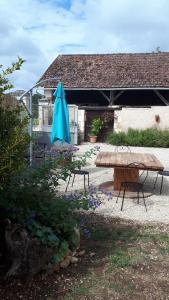 a picnic table with a blue umbrella in a yard at Maison à la Campagne in Blis-et-Born