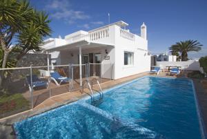 ein Haus mit einem Pool vor einem Haus in der Unterkunft Casa Jasmine - lovely Los Mojones villa WiFi heated pool short walk to beach in Puerto del Carmen