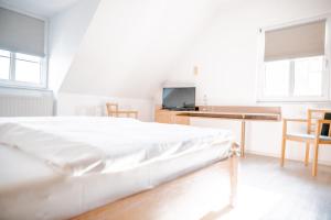 a white bedroom with a bed and a desk and chairs at Landhaus Bisping in Everswinkel
