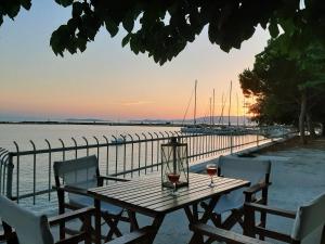 drewniany stół z dwoma kieliszkami wina obok wody w obiekcie Melia studio 2 seafront apartment w mieście Lutraki