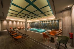 a hotel lobby with a swimming pool and chairs at Catalonia Donosti in Donostia-San Sebastián