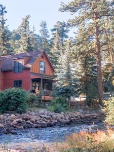 a red house with a river in front of it at Riverfront Mountain Cottage Retreat in Estes Park