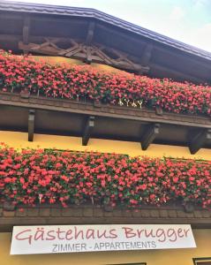 un cartel en un edificio con flores rojas. en Gästehaus Brugger Martin, en Sölden