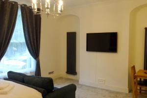 a living room with a couch and a television on the wall at Derwent View Holiday Apartments in Matlock
