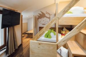 Habitación pequeña con litera y TV. en Kinderhotel Laderhof en Ladis