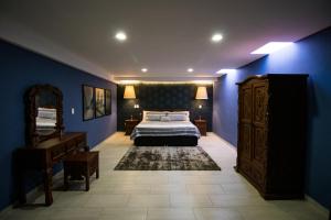 a bedroom with blue walls and a bed and a dresser at Hotel Santa Rosa by Rotamundos in Cholula