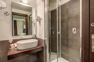 a bathroom with a shower, sink, and mirror at Hotel Rinascimento - Gruppo Trevi Hotels in Rome
