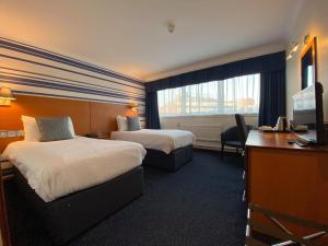 a hotel room with two beds and a desk and a television at The Liner at Liverpool in Liverpool