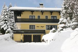 a yellow house in the snow with snow covered trees at Haus Klager in Ramsau am Dachstein