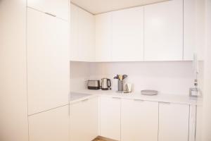 eine weiße Küche mit weißen Schränken und Geräten in der Unterkunft FLH Augusta's Arch Sophisticated Flat in Lissabon