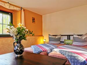 a bedroom with two beds and a vase with flowers on a table at Ferienwohnung Hegemühle in Geithain